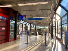 Metroasema, jossa on kirkasta auringonvaloa ja tyhjää tilaa. Sisäänkäynnin portit näkyvissä edessä.