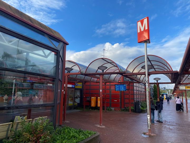 Itäkeskuksen metroaseman sisäänkäynti, jossa on punaista metallirakennetta ja lasikaton kaaria.