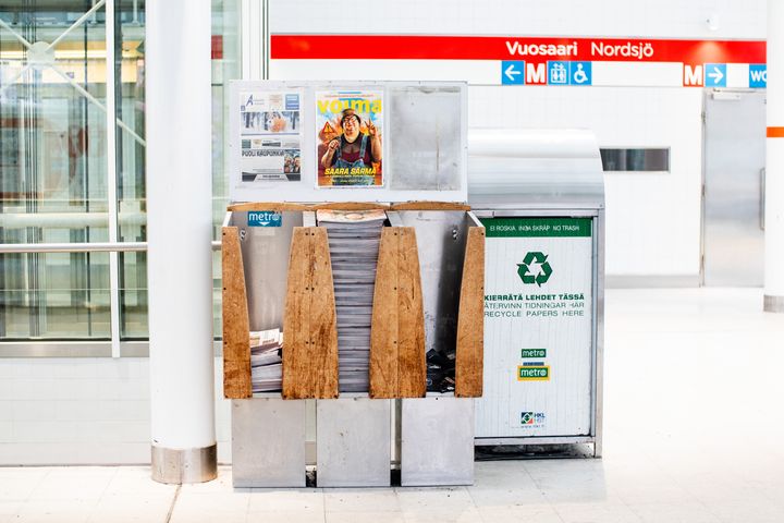 Lehtiteline ja keräysastia metroaseman lippuhallissa.
