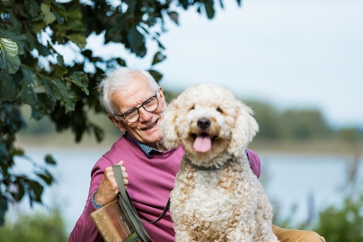 Valokuvassa mies istuu puiston penkillä koiran kanssa.