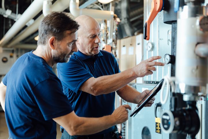 Kaksi miestä tutkii mittaria teknisessä tilassa.