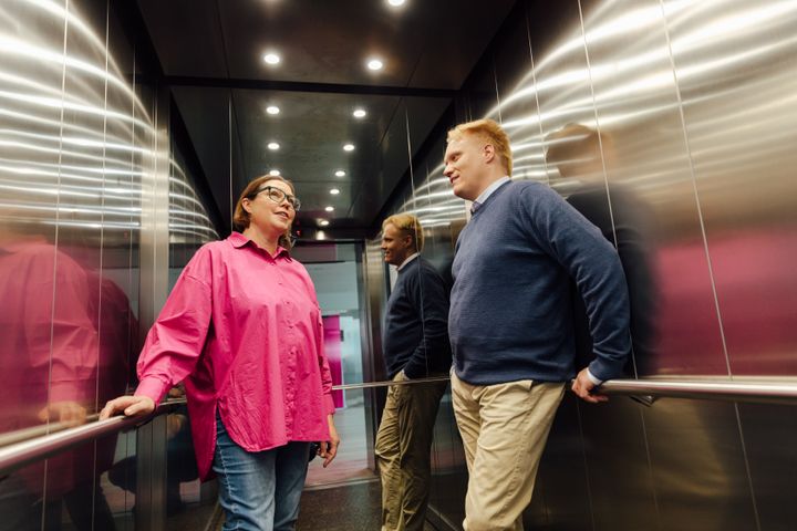 A women and a man talking in the lift at the office.