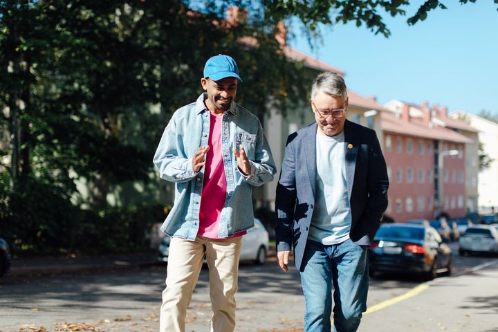 Two men walking on the street lively talking.