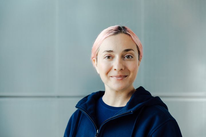 Valokuvassa nuori nainen katsoo hymyillen kameraan.