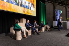 Paneelikeskustelu, jossa on viisi ihmistä lavalla. Yksi henkilö seisoo puhujanpöntön vieressä näyttäen puhuvan.