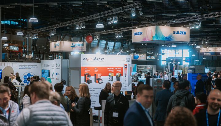 Ihmiset kävelevät ja keskustelevat Pulp & Beyond -messutapahtumassa, jossa on useita esiintymislavoja ja yritysten esittelykojuja.