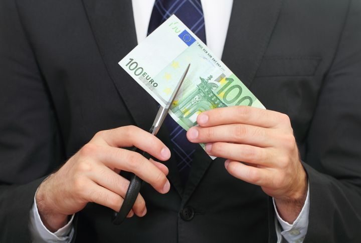 Pukumies leikkaa 100 euron seteliä saksilla