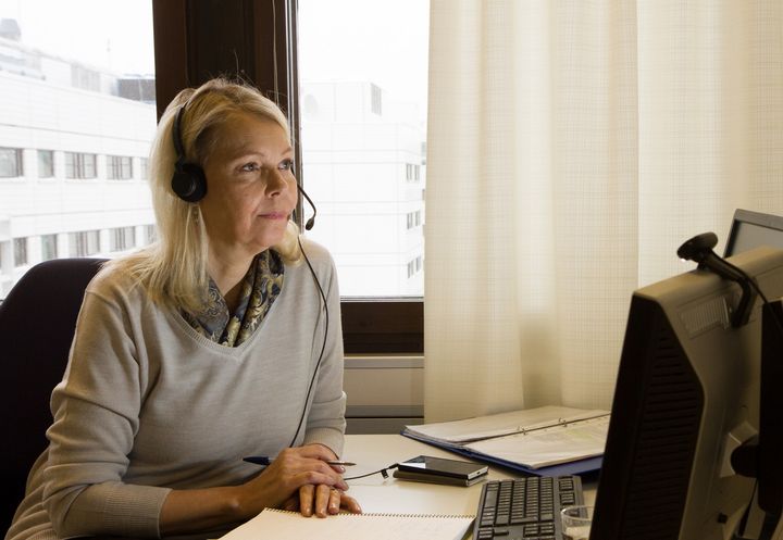 Kriisipuhelinvastaajanainen puhuu puhelimessa tietokoneen välityksellä