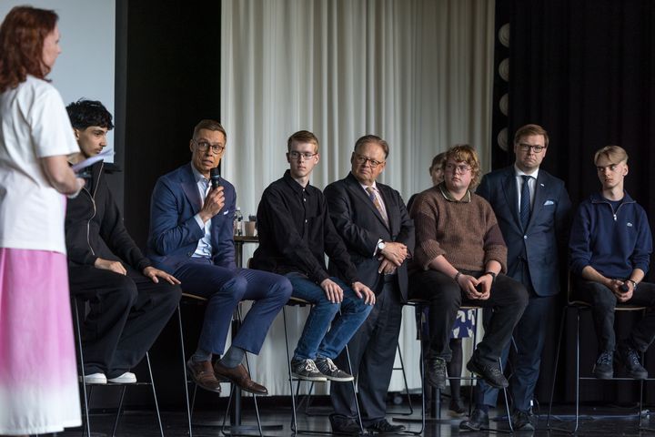 The President of the Republic of Finland, Alexander Stubb, is sittin on stool while discussing with students at Vesala Primary School.