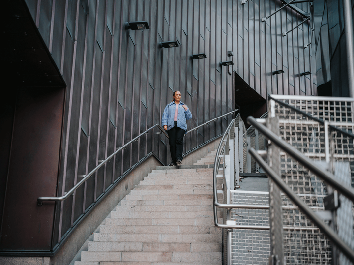 Henkilö kävelee alas portaissa metallisen rakennuksen edessä.