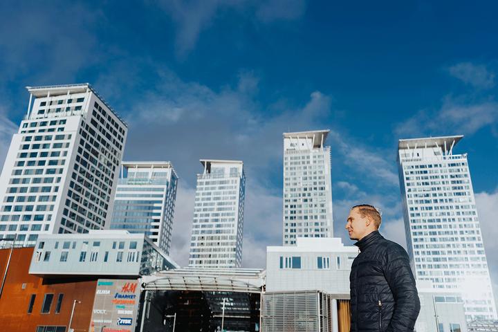 Mies seisoo taustalla näkyvien korkeiden rakennusten edessä.