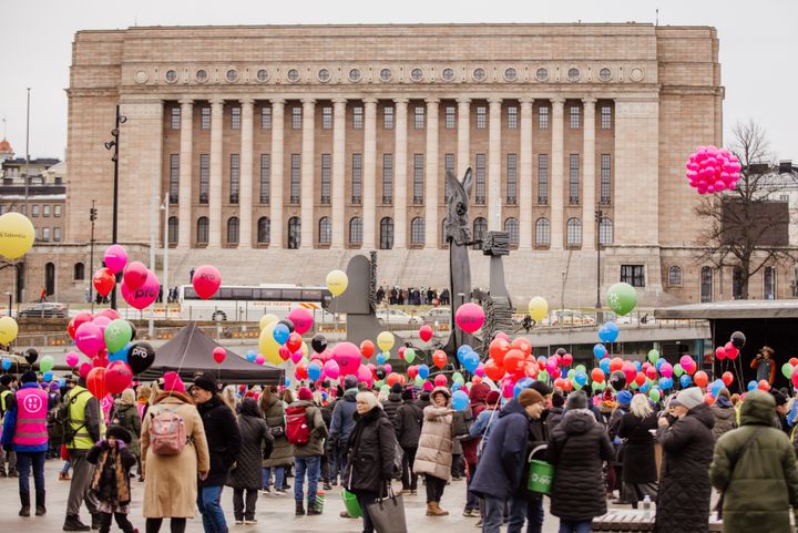Alt-teksti: Suuri joukko ihmisiä Kansalaistorilla värikkäiden ilmapallojen keskellä eduskuntatalon edessä marraskuussa 2023.