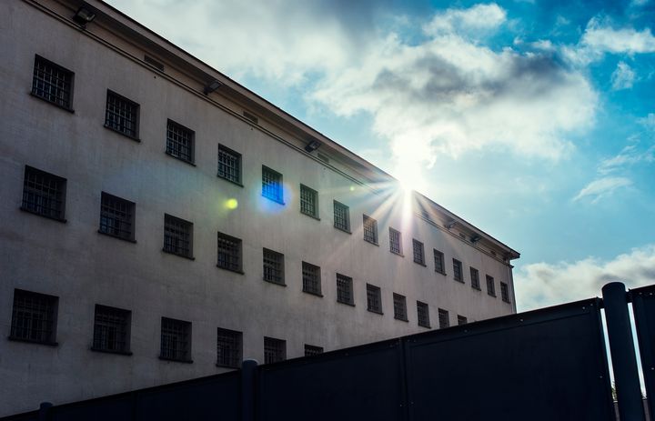 Vankilarakennuksen takaa paistaa aurinko.