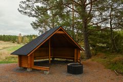 Laavu tulipaikkoineen puiden reunassa, takana peltomaisemaa.