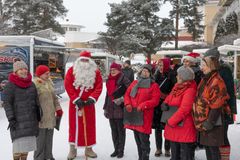 Joukupukki ja iloisia laulajia joulumarkkinoilla.