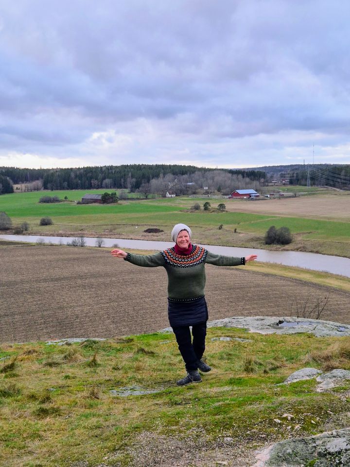 Niina Heikkilä kameran edessä peltomaisemassa.