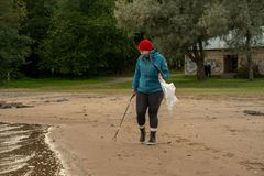 Henkilö siivoaa ranta-aluetta roskapihdeillä.