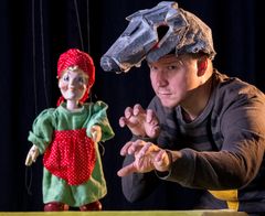 Nukketeatteriesitys Susi ja Punahilkka, jossa Punahilkka-nukke ja sudeksi naamioitunut ihminen.