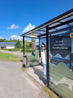 Bussipysäkki ja nainen seisoo siinä.