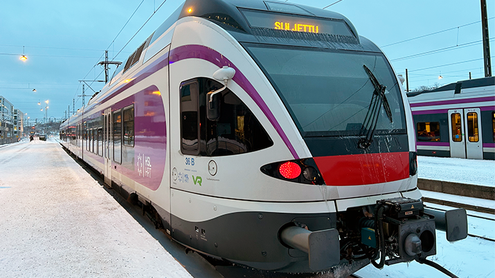 Lähijuna Helsingin rautatieasemalla talvelle 2023, hieman lunta maassa, aamunsininen taivas.