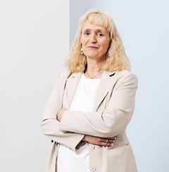 Vaaleahiuksinen nainen vaaleissa vaatteissa.