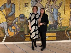 Kaksi naista vierekkäin kuvassa, taustalla taideteos.