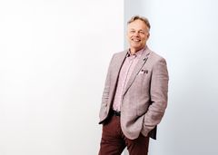 Mieshenkilö puvuntakki päällä katsoo kameraan.