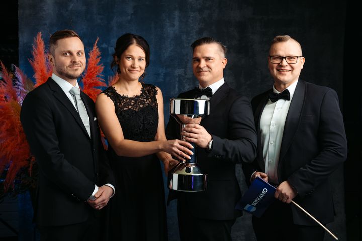 Henkilöt pitelemässä pokaalia.