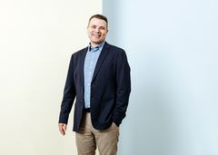 Mieshenkilö hymyilee ja katsoo kameraan.