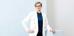 Naishenkilö valkoisessa bleiserissä.