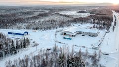 Korkealta kuvattu maisemakuva, jossa näkyy Muoniontie ja Kolarin Rakennustarvikkeen myymälä ja halli.