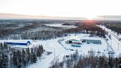 Korkealta kuvattu maisemakuva, jossa näkyy Muoniontie ja Kolarin Rakennustarvikkeen myymälä ja halli.