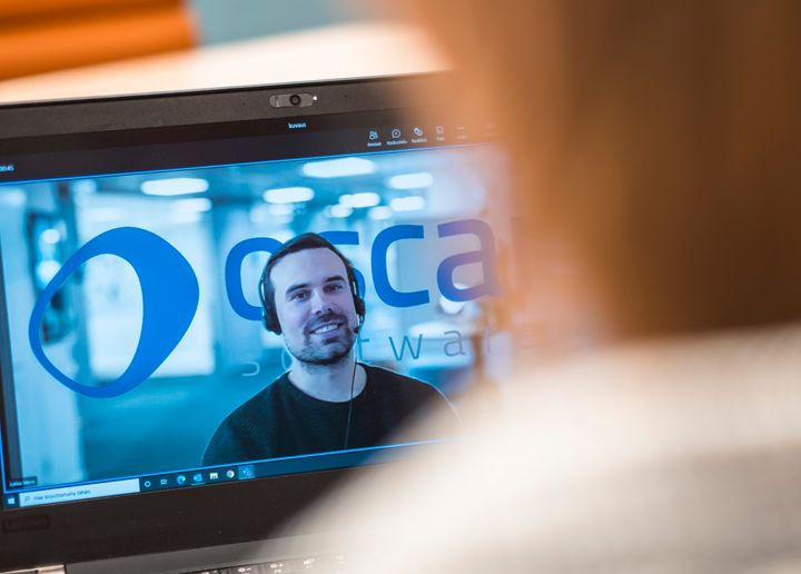 Tietokoneen näytöllä videopuhelu, jossa näkyy henkilö ja Oscar Software -logo.