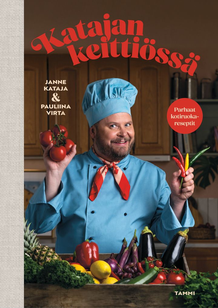 Kirjan kannessa kokkiasuinen Janne Kataja hymyilee ja pitelee tomaatteja sekä chilejä värikkäässä keittiössä. Taustalla lukee punaisella tekstillä Katajan keittiössä.