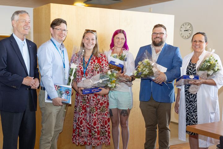En grupp människor som tar emot årets tvåspråkighetspris poserar tillsammans för ett foto med Nationalspråksnämndens ordförande Harry Bogomoloff.