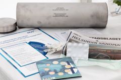 Bild på en tidskapsel av metall tillsammans med dokument, en tidning och andra små föremål.