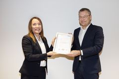 En man och en kvinna i kostymer håller tillsammans i ett certifikat.