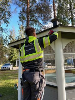 Henkilö maalaa pientä piharakennusta.