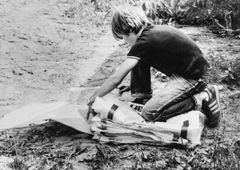 Nuori henkilö lajittelemassa säkkejä ulkona vuonna 1985.