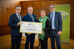 Neljä henkilöä seisoo ja pitelee suurta shekkiä, jossa lukee "Reilu Teko" ja lahjoitussumma 210 264,61 €. Taustalla Yara Suomi -banneri ja puurakenteinen seinä.