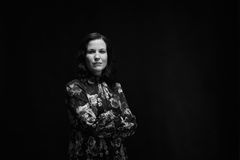 Mustavalkoinen kuva, jossa nainen seisoo vakavasti kädet puuskassa ja katsoo kameraan.