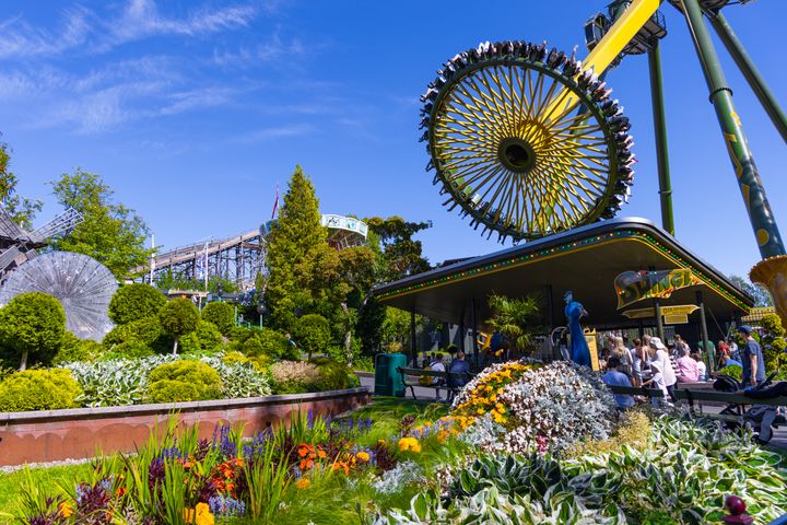 Linnanmäen huvipuisto, jossa on kukkapenkkejä etualalla ja suuri Swingi-huvipuistolaite taustalla.