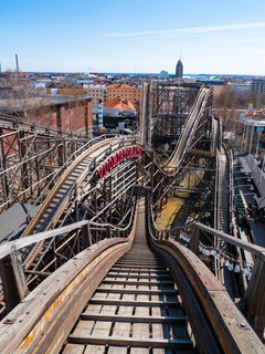 Puinen vuoristorata Linnanmäellä kuvattuna ylhäältä. Näkyy mutkitteleva rata, rakennuksia ja taustalla kaupungin siluetti.