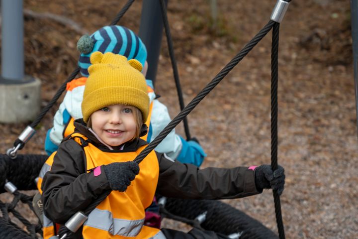 Children are swinging on a swing outside.