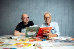 Mauri Kunnas ja Harri Römpötti lukevat Nyrok City -sarjakuvaa pöydän ääressä.