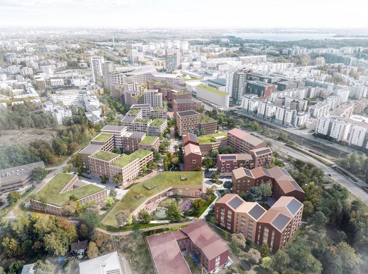 Aerial view showing apartment buildings, trees and green roofs in the foreground and the more densely built-up central area in the background.