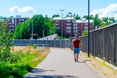 Henkilö kävelee kevyenliikenteen väylällä. Väylän oikeassa reunassa on puinen meluaita. Taustalla näkyy punainen kerrostalo.