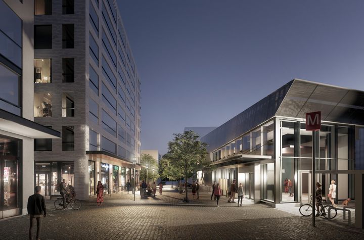 Näkymä Kaitaantieltä etelään päin. Metroaseman rakennus on kuvan oikealla reunalla ja vasemmalla puolella näkyy suunniteltujen uusien kerrostalojen julkisivuja, joiden maantasokerroksissa on liiketiloja. Kuvassa näkyy myös ihmisiä kuljeskelemassa.
