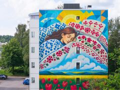 Kerrostalon seinässä on seinämaalaus, jossa henkilö nukkuu kirjailluiden liinavaatteiden keskellä. Seinämaalauksen alalaidassa on viljapelto, jossa kasvaa myös punaisia kukkia.