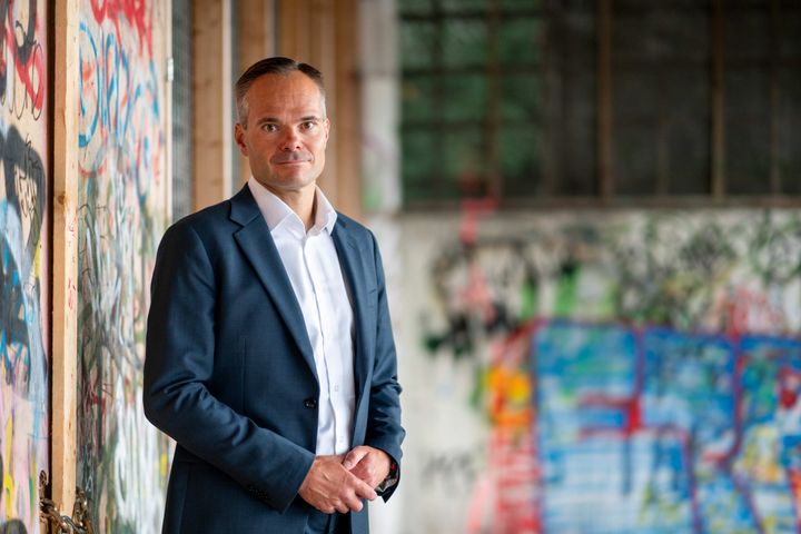 Kaupunginjohtaja Kai Mykkänen kuvattuna graffiteilla maalattujen seinien edessä.